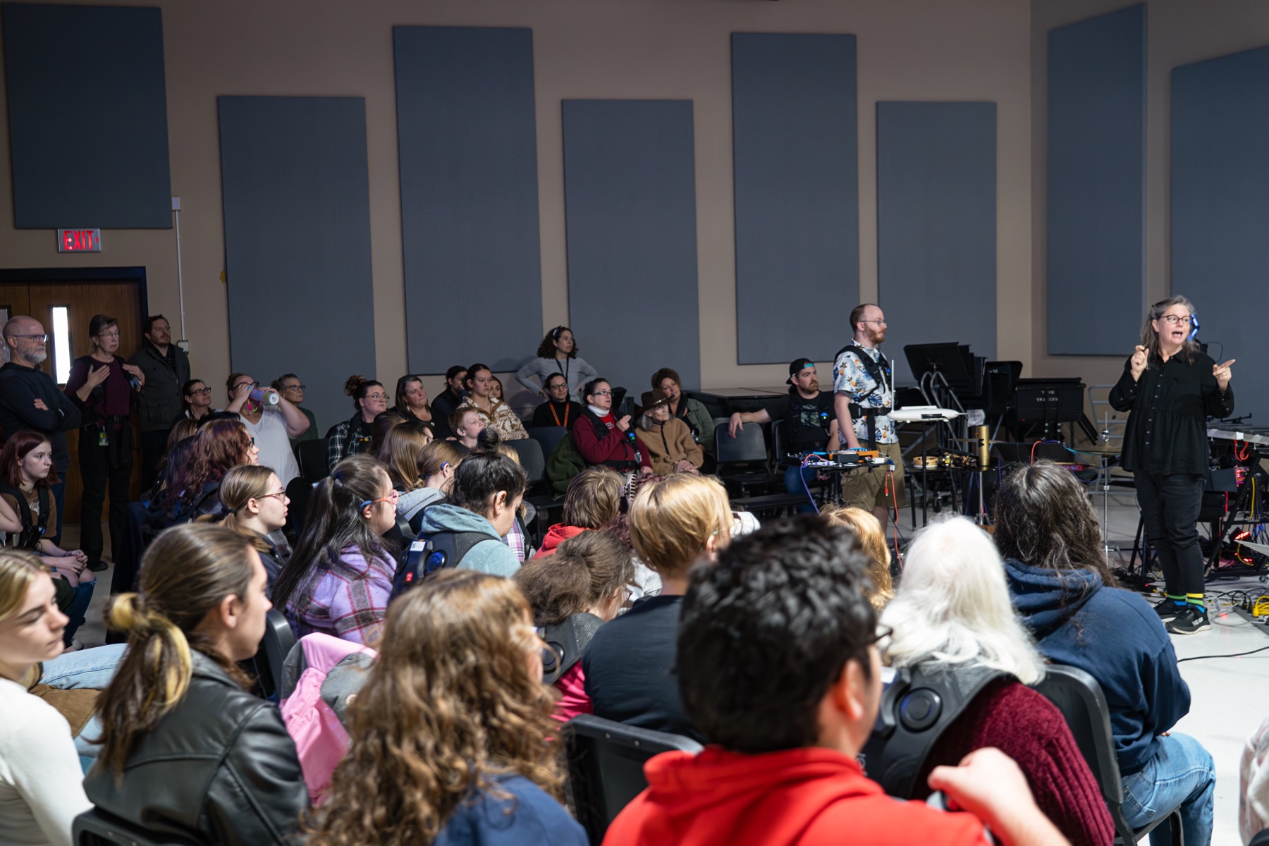 A packed lecture room at Southern Oregon University with an ASL interpreter signing at the front and roughly forty students watching a music technology demonstration.