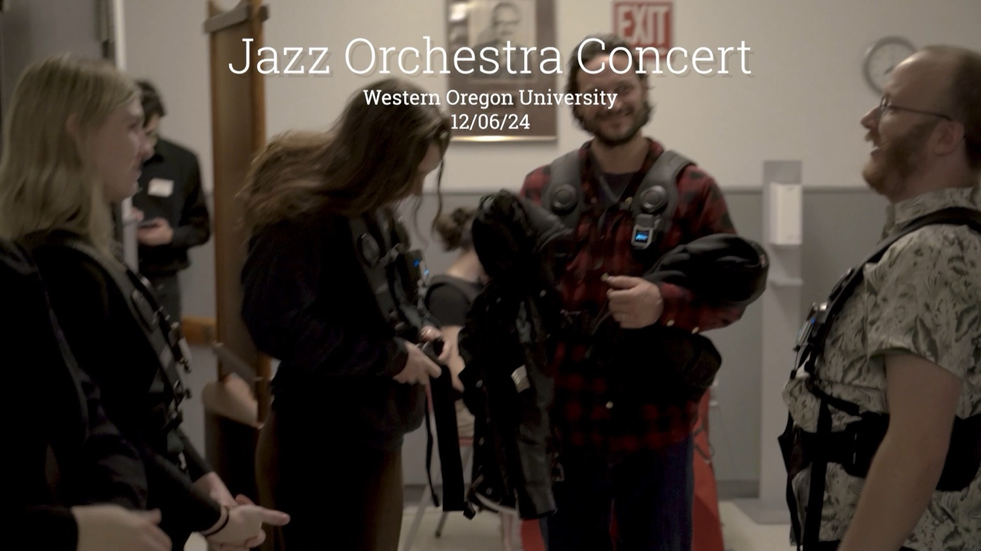 Participants helping each other fasten haptic vests before a jazz orchestra concert at Western Oregon University.